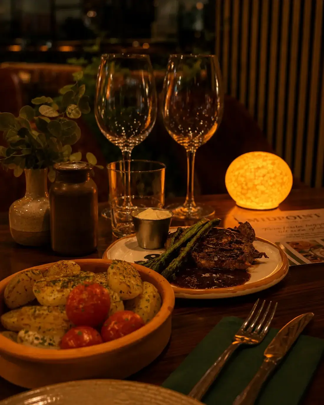 Entrecôte med rödvinssås, sparris och örtpotatis dukat med vinglas på Midpoint